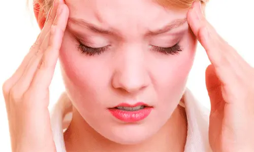 تصویر خانمی که دو دست خود را روی شقیقه گاه سرش گذاشته است برای وبلاگ روش های درمان میگرن در خانه